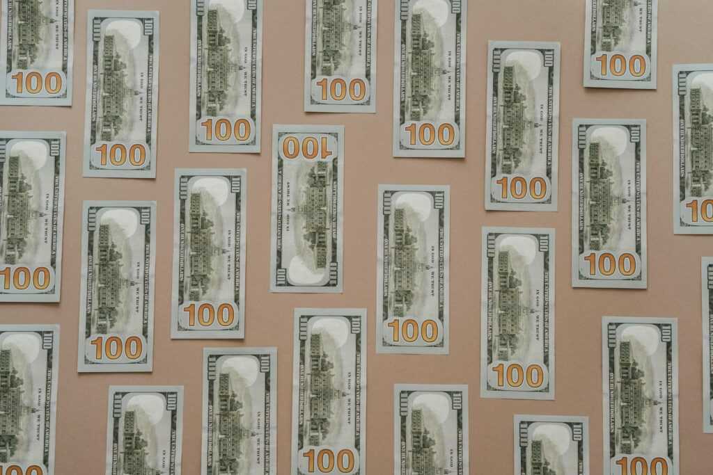 Flatlay of hundred dollar bills arranged on a surface representing wealth and finance.